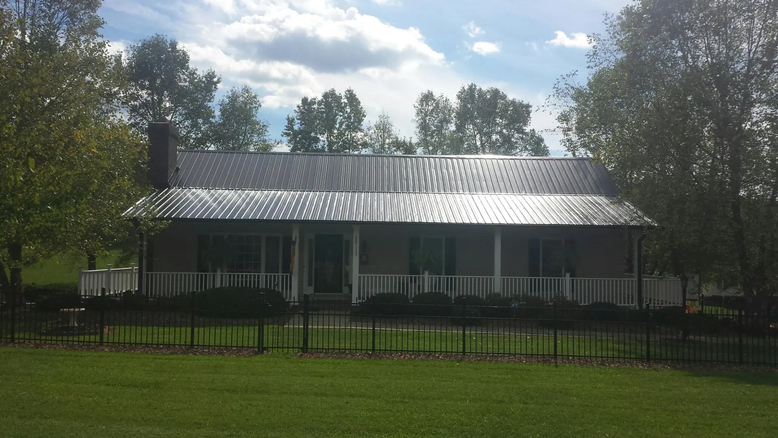 Gray metal roof on a brick ranch with a full width front porch — Gutter Guard Installation work by our crew in Marion