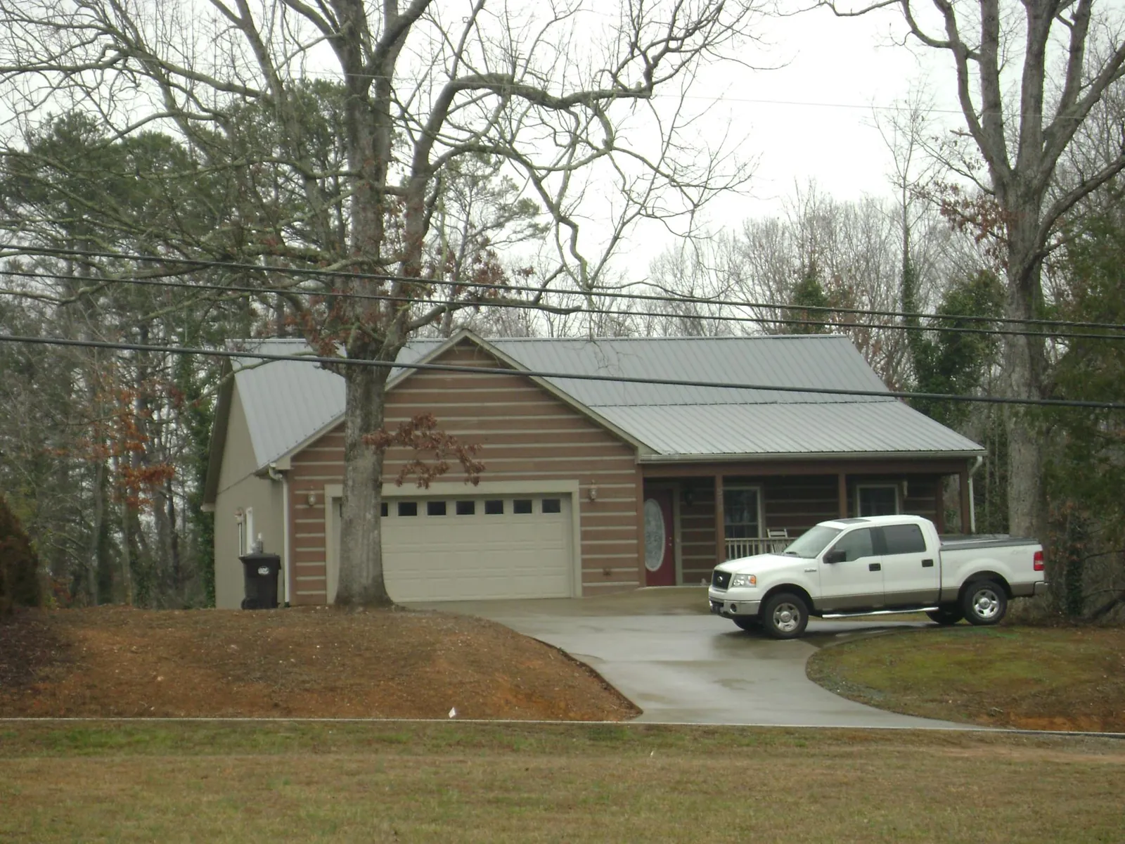 Gray metal roof on a log sided house with an attached two car garage in Marion